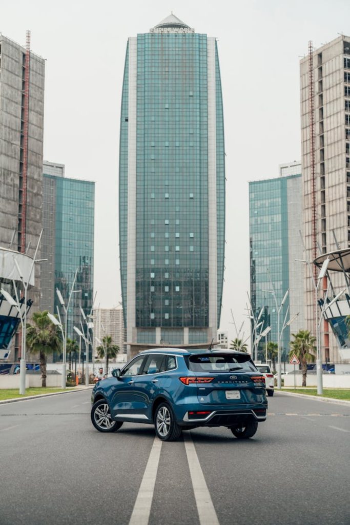 Blue SUV parked in front of a modern skyscraper in Erbil, showcasing urban architecture.